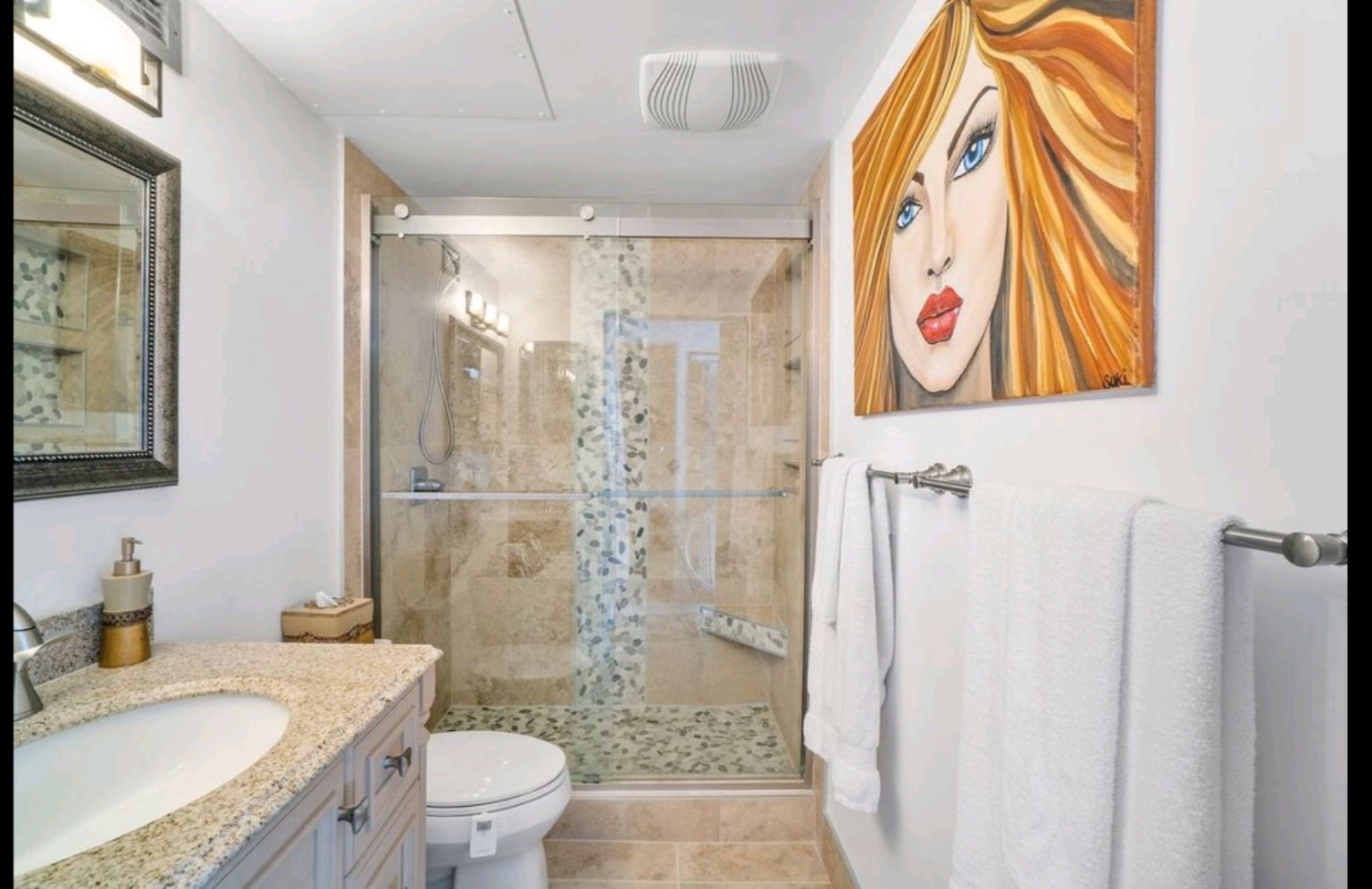 Full bathroom view showing the vanity and glass-enclosed travertine shower